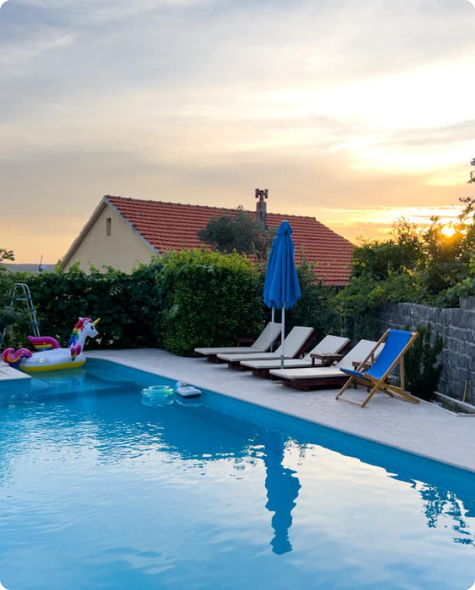 A backyard with deckchairs, a cleaned pool, and sunset
